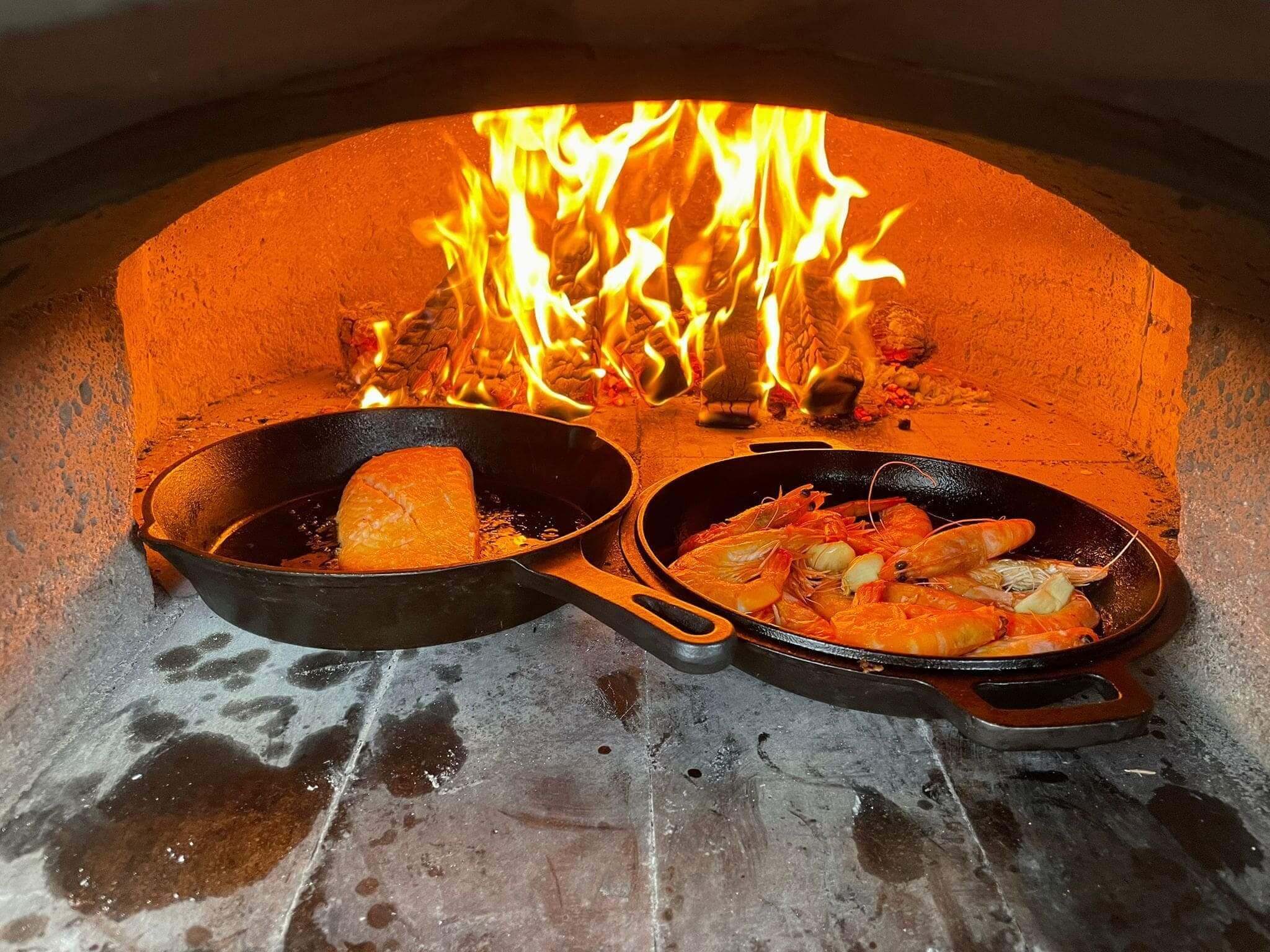 A seafood platter being cooked in a pizza oven which is perfectly